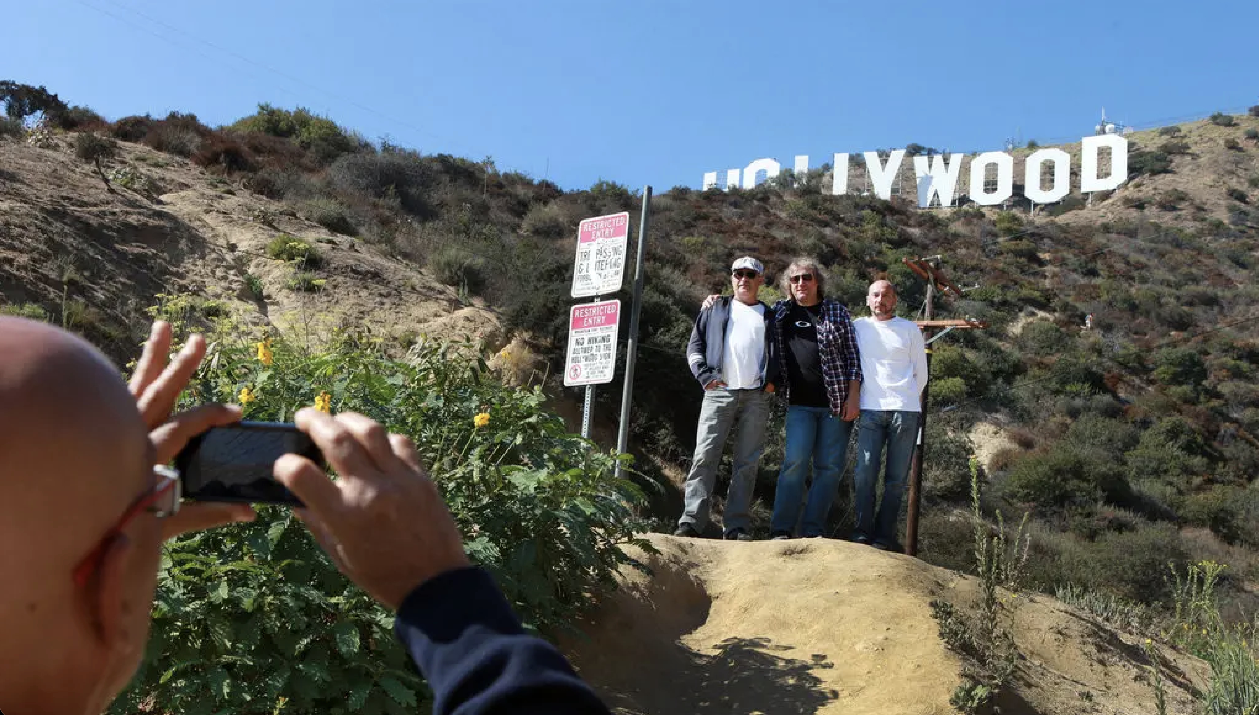 Visitors taking a group photo near the Hollywood Sign from The Last House on Mulholland viewpoint at 6101 Mulholland Hwy.